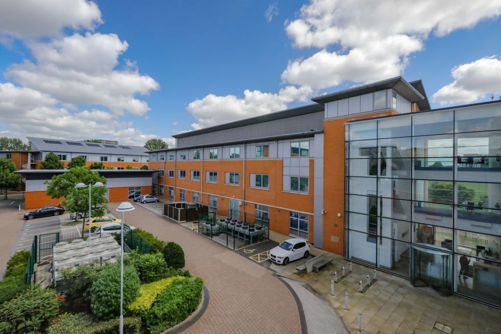 Exterior of the UKNode Manchester data centre — a modern multi-storey facility under blue sky.